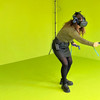 Eine Frau in einem Greenroom mit einer VR-Brille und einem Controller