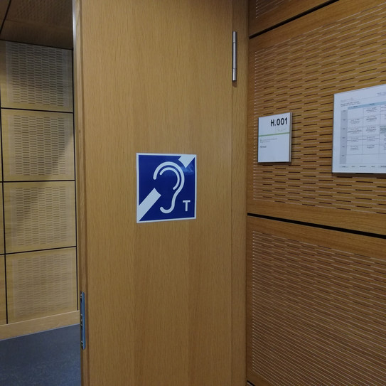 Hörsaaltür mit einem Schild des Symbolbilds für einen Hörschleife