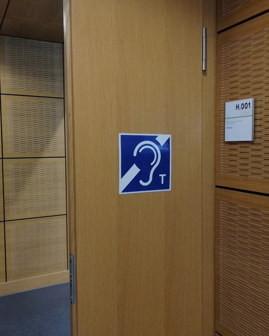 Auditorium door with a sign of the symbol image for an auditory loop