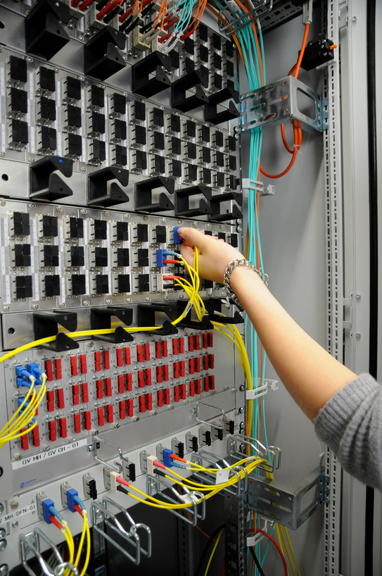Hand mit Stecker vor einen Server
