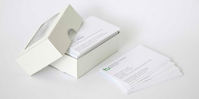 Geöffnete Schachtel mit Visitenkarten im TU Design sowie einige daneben liegende Karten