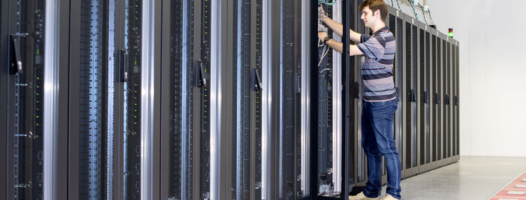 Employee stands in front of an open server cabinet in the ITMC
