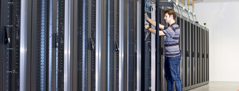 Mitarbeiter steht vor geöffnetem Serverschrank im ITMC