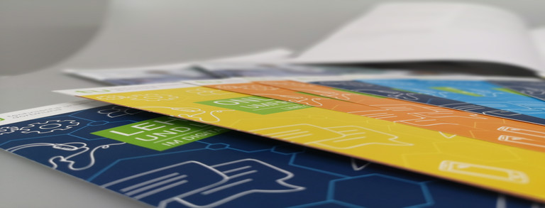 Several colorful flyers of the ITMC on top of each other