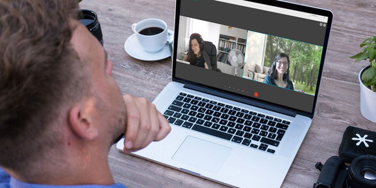 Mann bei einer Videokonferenz mit zwei Teilnehmerinnen auf dem Bildschirm 