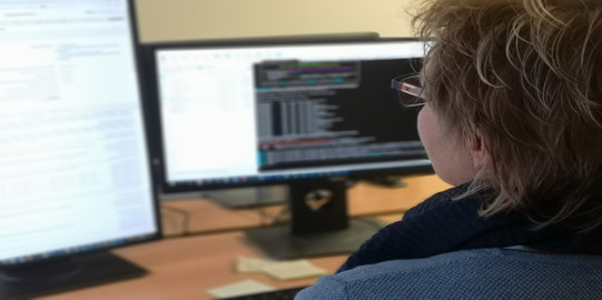 Programmer in front of two screens with programming code