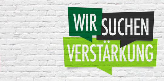 Verstärkung gesucht Weiße Mauer mit Schild "Wir suchen Verstärkung"