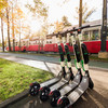 Im Hintergrund fährt eine Straßenbahn und im Vordergrund sind E-Scooter platziert.