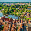 Lübeck aus der Vogelperspektive auf der man Wasser, Haussiedlungen und Wälder sehen kann.