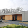 The large day care center is a modern building in grey with wooden facade elements. The picture shows the entrance to the building