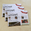 Three issues of unizet lie on top of each other on a table.