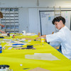 A boy in a lab coat is doing crafts at a table at TU Dortmund University's Boys*Day.