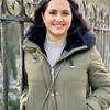 A woman smiles at the camera. She is standing in front of a fence.