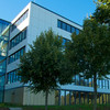 Ein Universitätsgebäude und Bäume vor blauem Himmel.