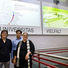 three people standing next to a railing. in the background are two pictureson a wall