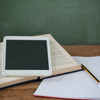 A tablet, a book and a notebook lie on a table