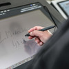 Screen of a lecture hall desk where someone is writing with a pen in hand.