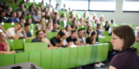 Lecturer sits in front of students in the lecture hall in the seminar building.