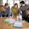 Five students stand around a table and look at a piece of paper.